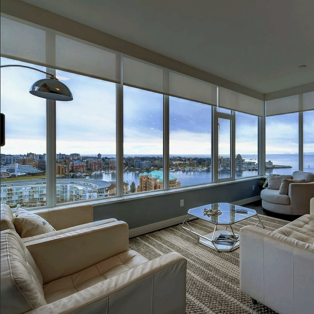 High-rise living room with expansive views of the waterfront and cityscape, featuring neutral-toned furniture in Victoria