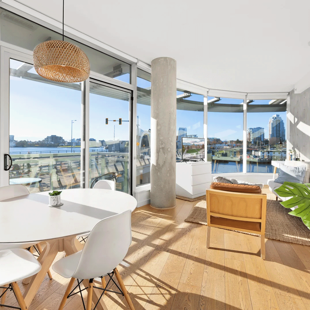 Modern dining space overlooking a bustling harbor, with stylish furnishings and ample natural light in Victoria