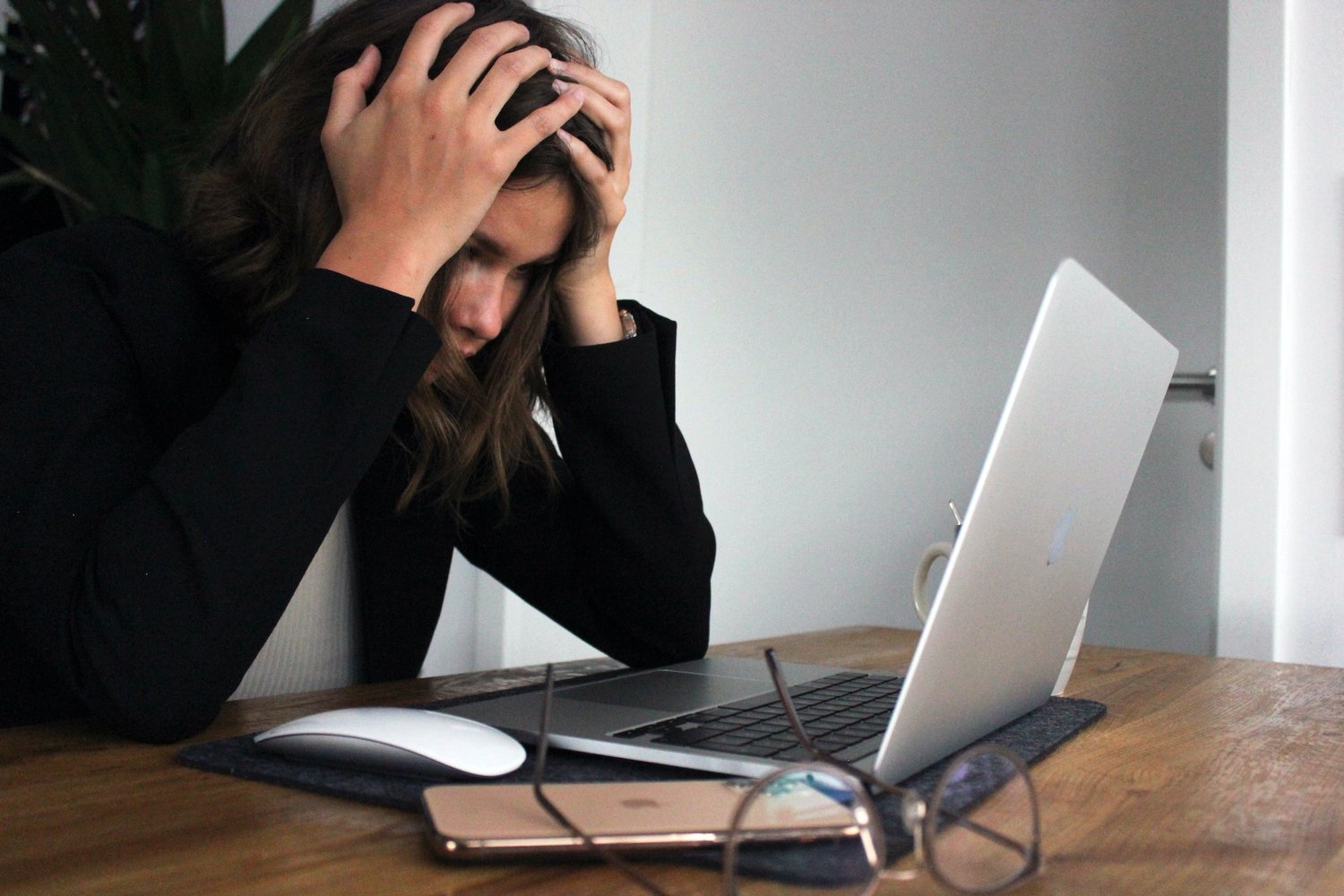 Distressed young woman in front of her computer at a cluttered desk, reflecting stress and work overload